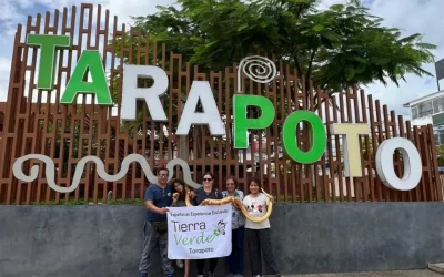 Grupo de turistas posando frente al letrero turístico de Tarapoto con banner de Tierra Verde, durante el city tour