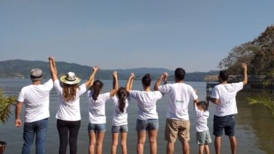 Familia unida de espaldas, tomada de la mano frente a la Laguna Azul en Sauce, San Martín.